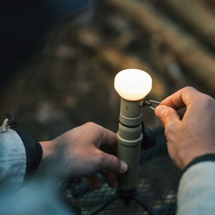 beige flashlight accessory attached to NESTOUT portable rugged battery on tripod being used for camping | innovative outdoor technology